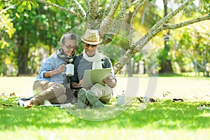 Asian Lifestyle senior couple drinking coffee and shopping online  in the nature park happy and relax time.Â 